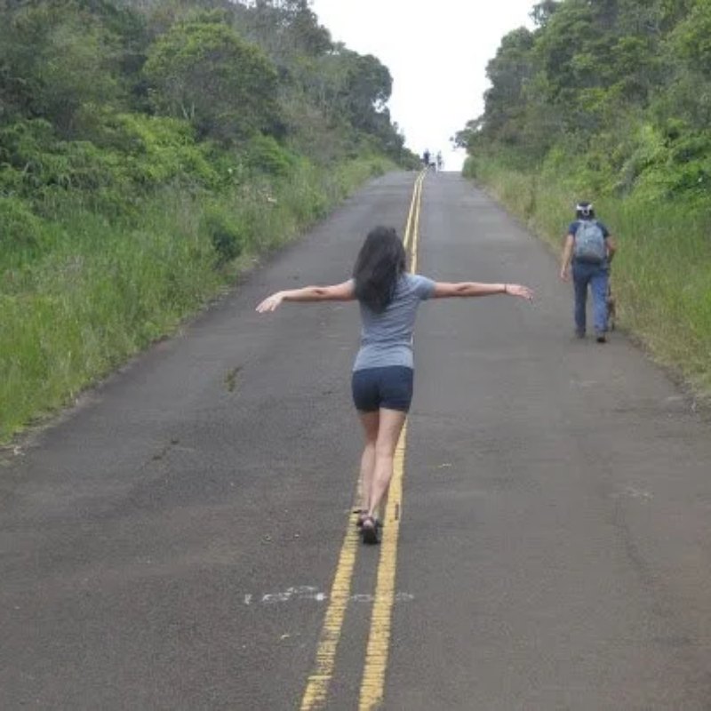 Jasmine walking down the middle of a quiet road with arms out